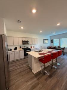 une cuisine avec des placards blancs et un îlot de cuisine avec des chaises rouges dans l'établissement Cozy Magnolia 4BR 3BA Family Home Retreat, à Magnolia
