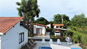 a house with a patio and a yard with white chairs at Cabaña Maria José in Moñitos
