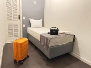 サンパウロにあるHotel SP Centroの部屋にあるオレンジ色のスーツケースが置かれたベッド
