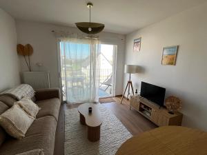 a living room with a couch and a tv at At Home Ste Cécile in Camiers
