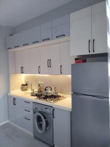 a white kitchen with a stove and a refrigerator at Abşeron City yaşayış kompleksi in Sumqayyt