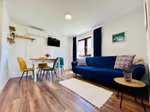 ein Wohnzimmer mit einem blauen Sofa und einem Tisch in der Unterkunft Apartments Celopek in Ličko Petrovo Selo