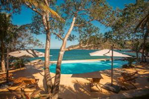 a pool with chairs and umbrellas next to the ocean at Corrales Bay Resort in Corrales