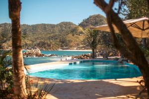 a swimming pool next to a beach with a body of water at Corrales Bay Resort in Corrales