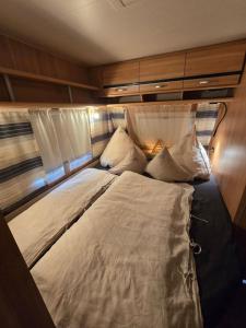 a large bed with pillows in a room at Rosenzauber Caravan in Münchberg