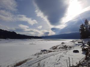 a view of a snow covered river with the sun shining at Hanguloft - The cozy cabin by the lake in Hangul