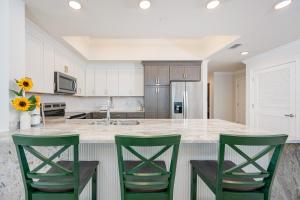 オレンジビーチにあるPhoenix X 102 condoの緑の椅子3脚とカウンターのあるキッチン