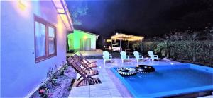 a swimming pool with white chairs and a house at Cabaña Maria José in Moñitos