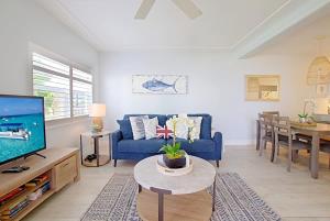 a living room with a blue couch and a tv at Plantation Village #20 Condo in Seven Mile Beach