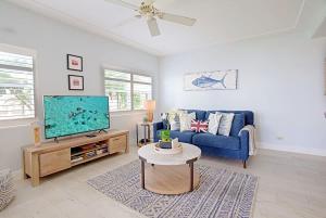 a living room with a blue couch and a tv at Plantation Village #20 Condo in Seven Mile Beach