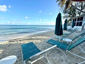 a group of chairs and umbrellas on a beach at Plantation Village #37 Condo in Seven Mile Beach