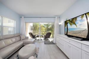 a living room with a couch and a large screen tv at Plantation Village #37 Condo in Seven Mile Beach