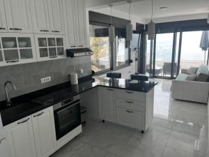eine Küche mit weißen Schränken und ein Wohnzimmer in der Unterkunft ALOHA Beach front Vacation Rental in Ulcinj