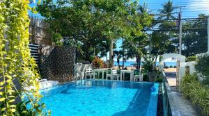 a swimming pool with a table and chairs next to the beach at Beach Gallery House in Jomtien Beach