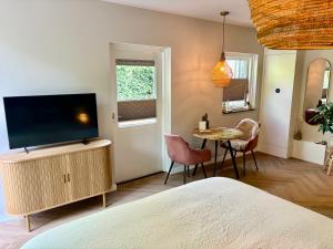 a bedroom with a flat screen tv and a table at Bij Julia in Den Burg
