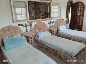ein Zimmer mit zwei Betten und einem Spiegel in der Unterkunft Authentic Guesthouse with Garden and Mountain View Beni Mellal in Beni Mellal