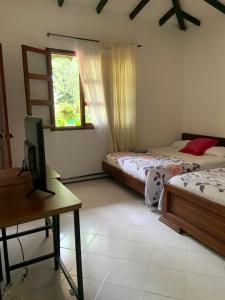 una stanza con due letti, una scrivania e una televisione di cabaña grande ecopolis hospedaje a El Queremal