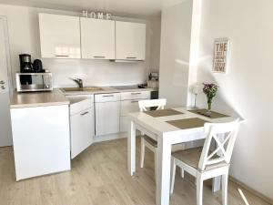 a kitchen with white cabinets and a table and chairs at Leuchtturm in Juist