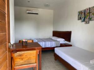 a bedroom with two beds and a desk and a door at Hotel luz de luna in Mahahual