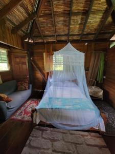 a bed with a mosquito net in a room at Tia's Bamboo Cottages Restaurant, Bar & Sulphur Spa in Roseau