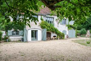 an old house with a dog sitting in front of it at Maison avec piscine, proche Chenonceau et Amboise in La Croix-en-Touraine