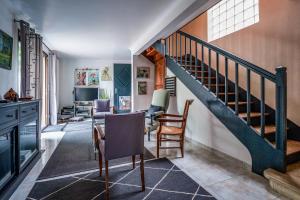 a living room with a staircase and a table and chairs at Maison avec piscine, proche Chenonceau et Amboise in La Croix-en-Touraine