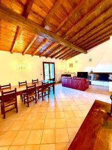 un ampio soggiorno con un lungo tavolo e soffitti in legno di Villa Lilly - 20 min da Maranello a Serramazzoni