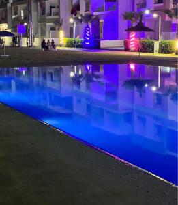 a swimming pool at night with lights in a building at Appartement vu sur piscine à 5 minutes de la plage in Mansouria