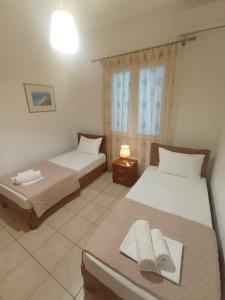 a bedroom with two beds and a lamp and a window at Sweet Home Lefkas in Lefkada