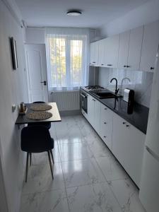 a kitchen with white cabinets and a table and a sink at Apartment Central in Onești