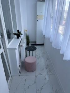 a white hallway with a stool and a table at Apartment Central in Onești