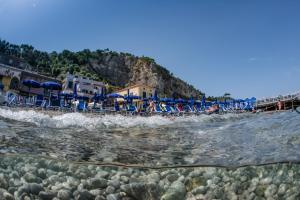 a beach with chairs and umbrellas and the water at Hotel Baia Di Puolo in Massa Lubrense
