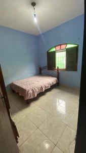ein Schlafzimmer mit einem Bett in einem Zimmer mit einem Fenster in der Unterkunft Casa in Mongaguá