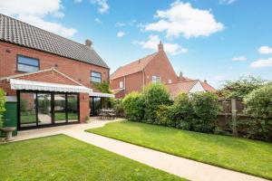 a garden with a brick house with a lawn at Pound Cottage in Holt