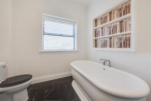 a bathroom with a white tub and a toilet at Pound Cottage in Holt +12 photos