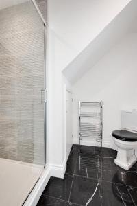 a bathroom with a toilet and a glass shower at Pound Cottage in Holt