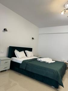 a bedroom with a bed with green sheets and white pillows at T&T Studio in Râmnicu Vâlcea