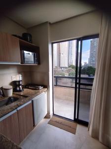 een keuken met een glazen schuifdeur naar een balkon bij Studio Urbano Sun Square hotel in Goiânia