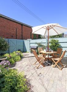 ein Tisch und Stühle mit einem Sonnenschirm auf einer Terrasse in der Unterkunft Oyster Cottage in Southwold
