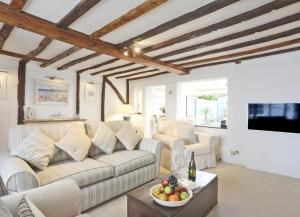 ein Wohnzimmer mit einer Couch und einem Tisch mit einer Obstschale in der Unterkunft Oyster Cottage in Southwold