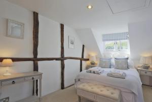 ein Schlafzimmer mit einem Bett, zwei Tischen und einem Fenster in der Unterkunft Oyster Cottage in Southwold