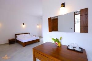 a bedroom with a bed and a table and a mirror at Castello Hotel in Polonnaruwa