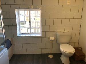 a bathroom with a toilet and a window at Jasmine Cottage in Woodbridge