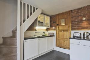 a kitchen with white cabinets and a staircase at Jasmine Cottage in Woodbridge +4 photos