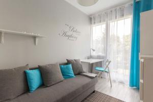 salon z szarą kanapą i niebieskimi poduszkami w obiekcie Apartamenty Startowa Gdańsk w Gdańsku