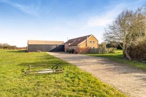 a barn and a house and a grass field at West Barn Cottage in Aldringham
