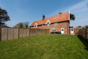 a brick house with a fence and a yard at The Old Hall Farm House in Reydon