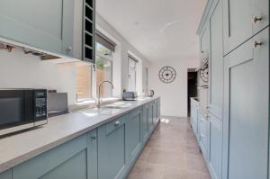 eine Küche mit blauen Schränken, einer Spüle und einer Mikrowelle in der Unterkunft James Cottage in Southwold + 10 Fotos
