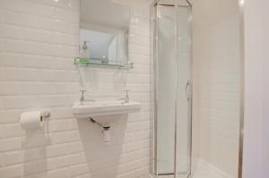 ein weißes Badezimmer mit Waschbecken und Dusche in der Unterkunft James Cottage in Southwold