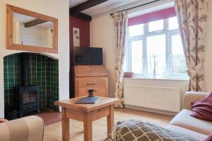 ein Wohnzimmer mit Kamin und Fernseher in der Unterkunft Kingfisher Cottage in Youlgreave